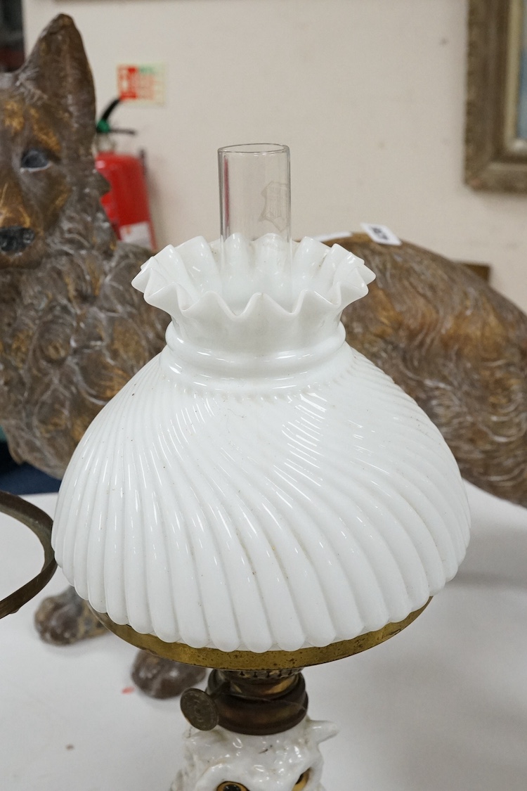 A pair of Paris porcelain oil lamps with white glazed porcelain stems modelled as owls (one lacking shade), 40cm high. Condition - fair